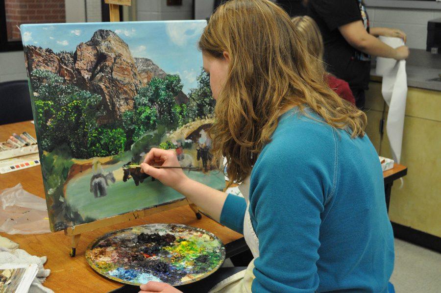 Rachel Scott works on a painting of people riding horses crossing a river.