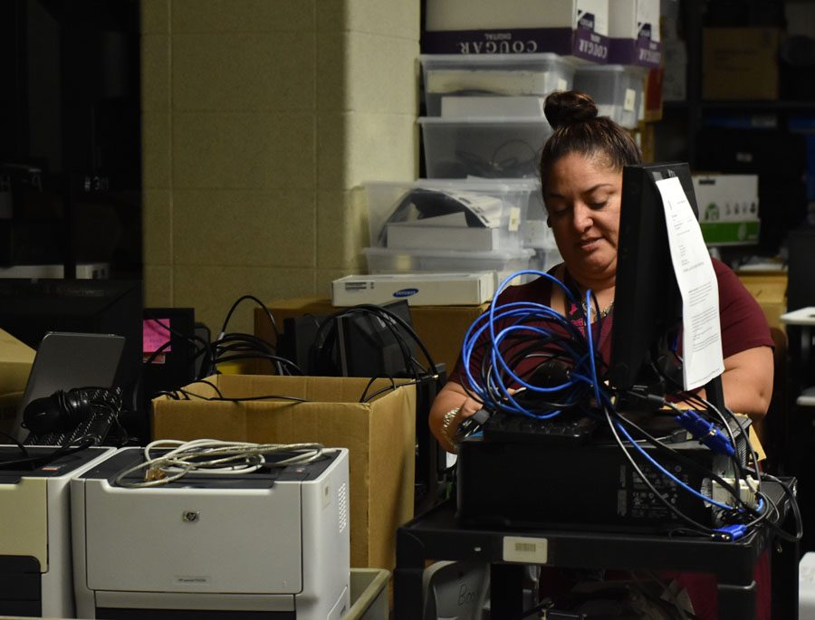 K-Park IT head Myriam Vargas moves a cart with a broken computer monitor on it in the technology storage room. 
