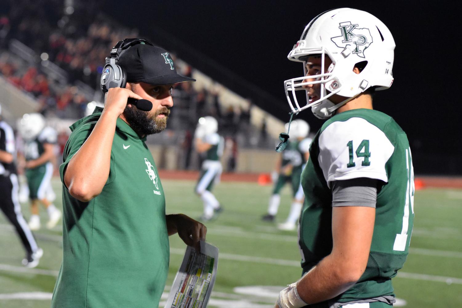 While the defense is on the field, offensive coordinator Bruce Cox uses his headset to talk with the coaches watching from the Press Box as he gives tips to senior quarterback Sam Johansen.