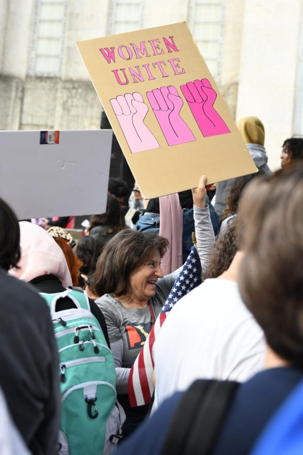 A woman wearing a Women’s March shirt laughs while holding a sign reading “Women Unite” at the fourth annual Women’s March in Houston.
