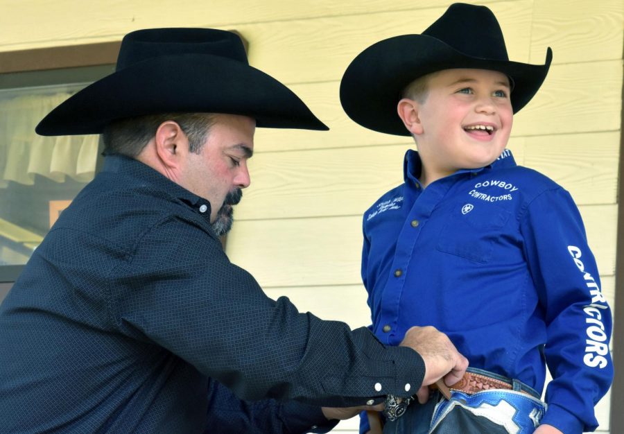 Jeff Wilson adjusts the gear his son Shiloh, 7, wears each time he competes in saddle bronc riding at rodeos. His father, who teaches collision and refinishing, retired from rodeo in 2004. He was a saddle bronc champion in 2002. 