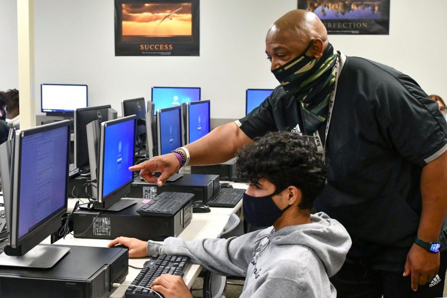 Business teacher James Showers works with a student in Money Matters class during sixth period on May 11. 