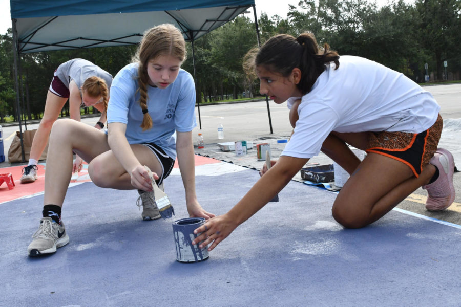 With help from juniors Emma Yeager and Katie Gerbasich, senior Kathleen Ortiz paints her parking spot on Sept. 4.