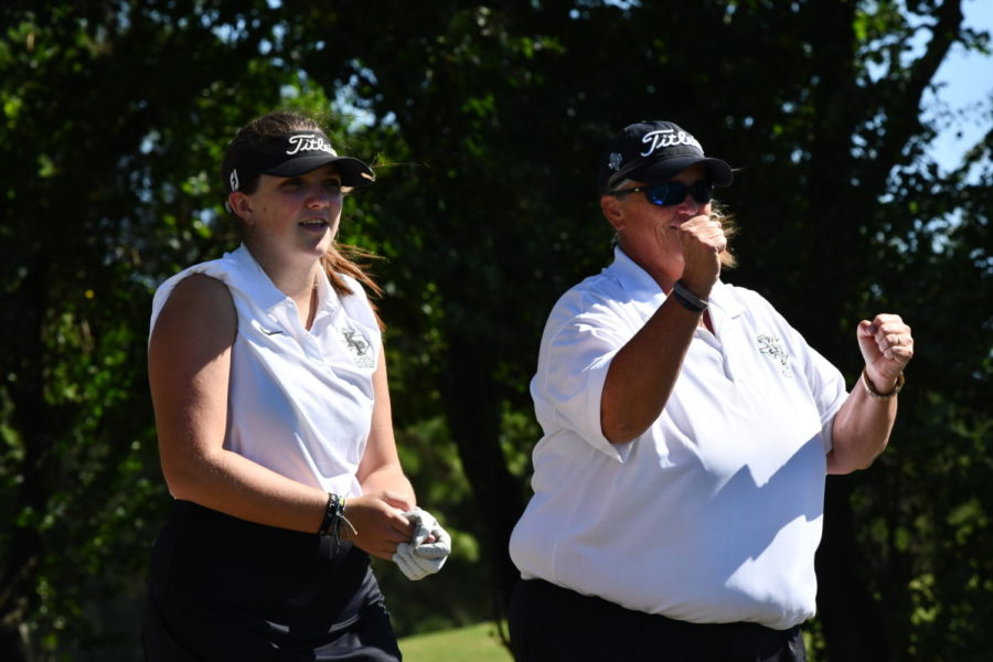 Kaitlyn Neel and Coach Chancellor watch and wait as Courtney Daniel finishes putting on the first hole. 
