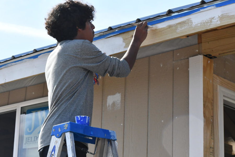 Junior Osvaldo Jasso paints trim near the roof of the architecture teams latest Tiny Home. 
