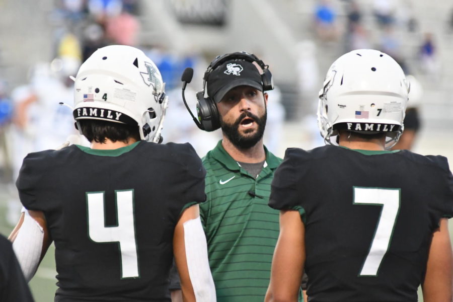 Coach Kyle Grimes talks to players during a football game in the fall. 