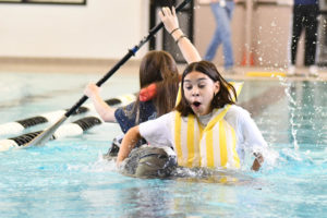 Junior Yailette Ibarra falls into the pool as teammate Favor Rogers continues trying to steer their sinking boat during fourth period. 
