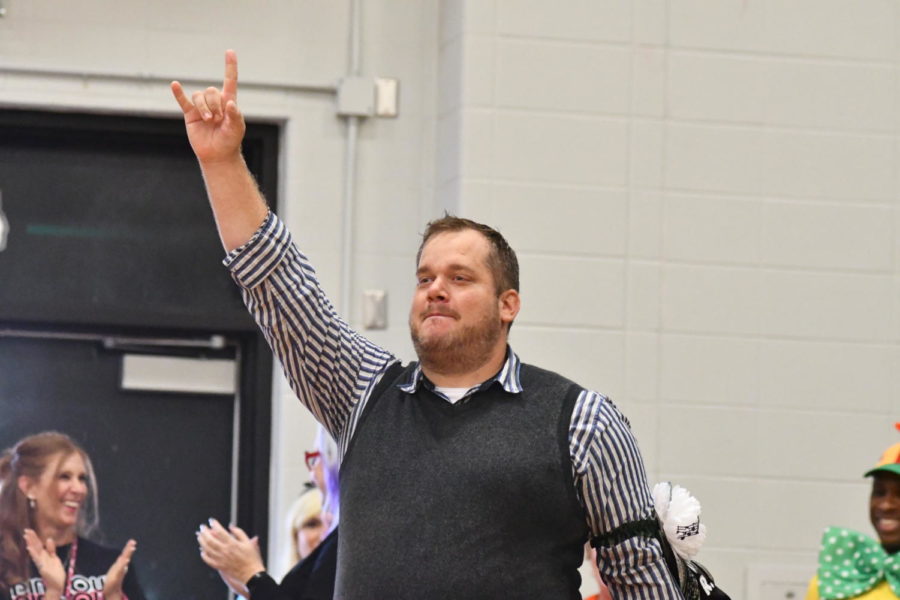 Band teacher Bryan Hess signals to his fans during the Homecoming pep rally when he was celebrated as being part of the faculty homecoming court. 