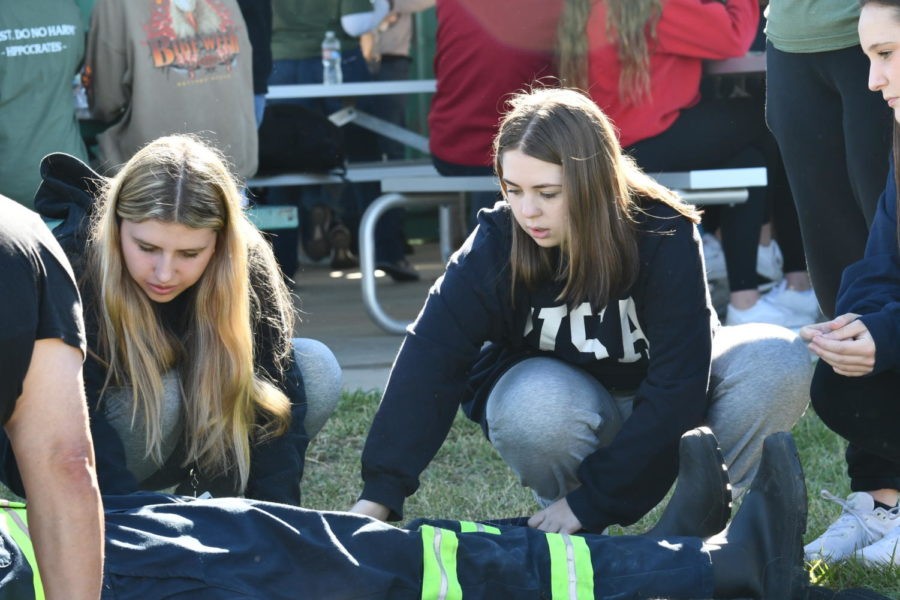 Makena Thomas and Anna Claire Kohnke examine a body at one of the stations during the HOSA field trip on Oct. 19.