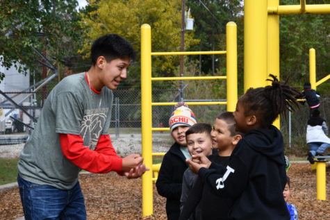 Freshman Eduardo Hernandez plays rock-paper-scissors with students during recess at Jack Field Elementary during Day of Service.