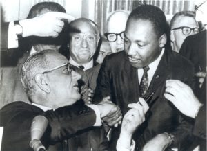 President Lyndon Johnson shakes hands with the Reverend Martin Luther King, Jr., after handing him one of the pens used in signing the Civil Rights Act of July 2, 1964 at the White House in Washington.