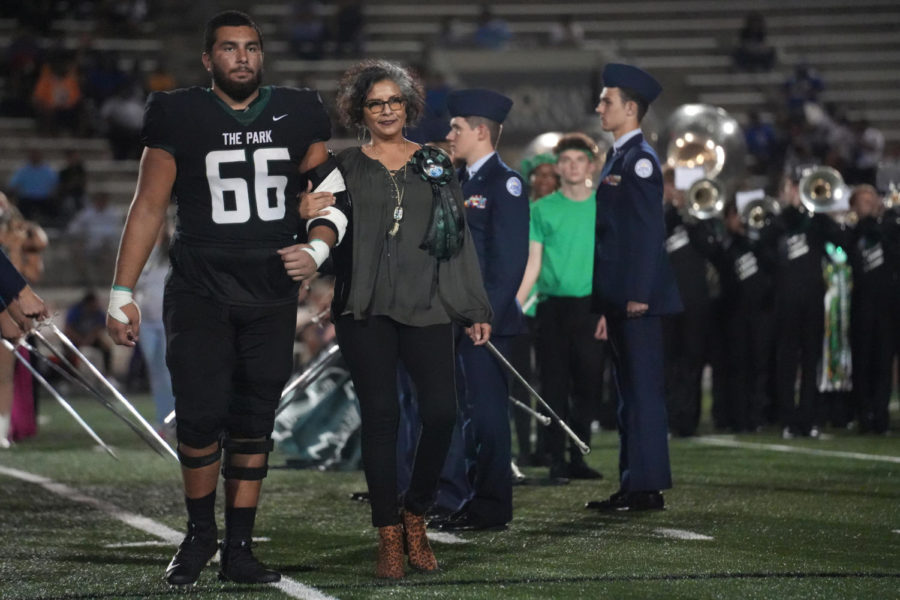 Erick Zapata and his mom Edna Peña walk out at midfield at halftime of the homecoming football game. Zapata was a homecoming king nominee.