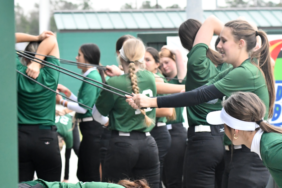 Junior Bailey Kee stretches with her teammates in the dugout before a practice in January. 