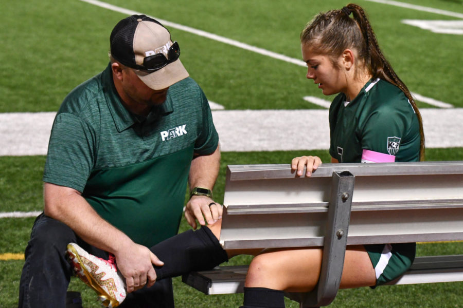 Head+athletic+trainer+Daniel+Scalia+looks+over+the+right+knee+of+senior+Bailey+Ricker+during+the+girls+soccer+game+against+Porter+on+March+3.+Ricker+tore+her+ACL+in+her+right+knee+during+her+sophomore+year.