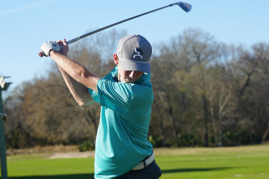 Senior Jayden Romig is in his backswing while he hits a iron shot of the practice range during practice on Jan. 19.