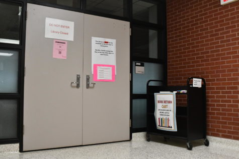 A cart sits outside the library entrance each day. Librarian Jessica Castille stands nearby during Flex Hour to assist students who may have questions or need to return items or pay fines.