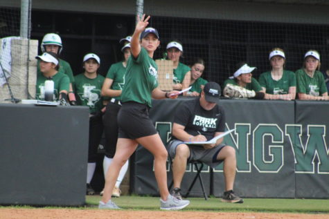 Coach Kelsie McEachern signals a play to a runner at first base.