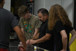 Auto collision teacher Jeff Wilson works with students in class during a project.