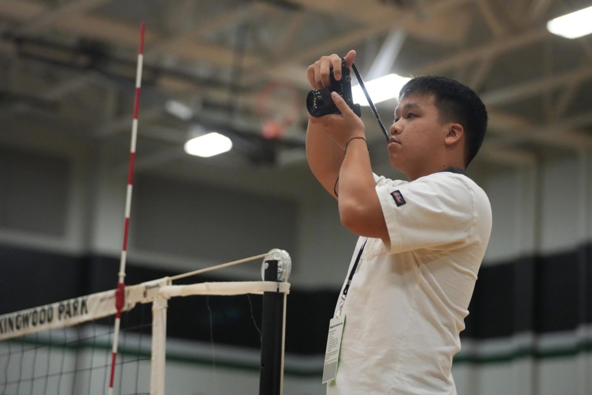 Senior+James+Pham+stands+on+the+referee+stand+prior+to+the+start+of+the+varsity+volleyball+game+against+Baytown+Sterling+on+Aug.+22.+Pham+started+shooting+sports+photos+for+the+yearbook+and+newspaper+staff+last+year+when+he+moved+to+Kingwood+Park+from+Bellaire+High+School.+