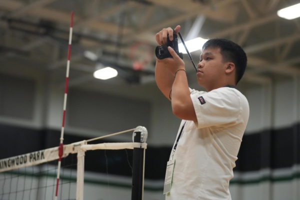 Senior James Pham stands on the referee stand prior to the start of the varsity volleyball game against Baytown Sterling on Aug. 22. Pham started shooting sports photos for the yearbook and newspaper staff last year when he moved to Kingwood Park from Bellaire High School. 
