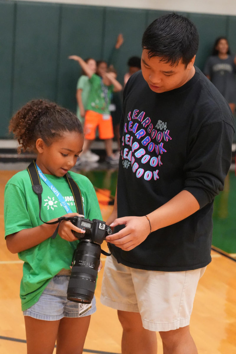 Senior James Pham works with a camper at the summer KPHS Summer Media Camp. He helped teach elementary and middle school students how to use the journalism cameras.