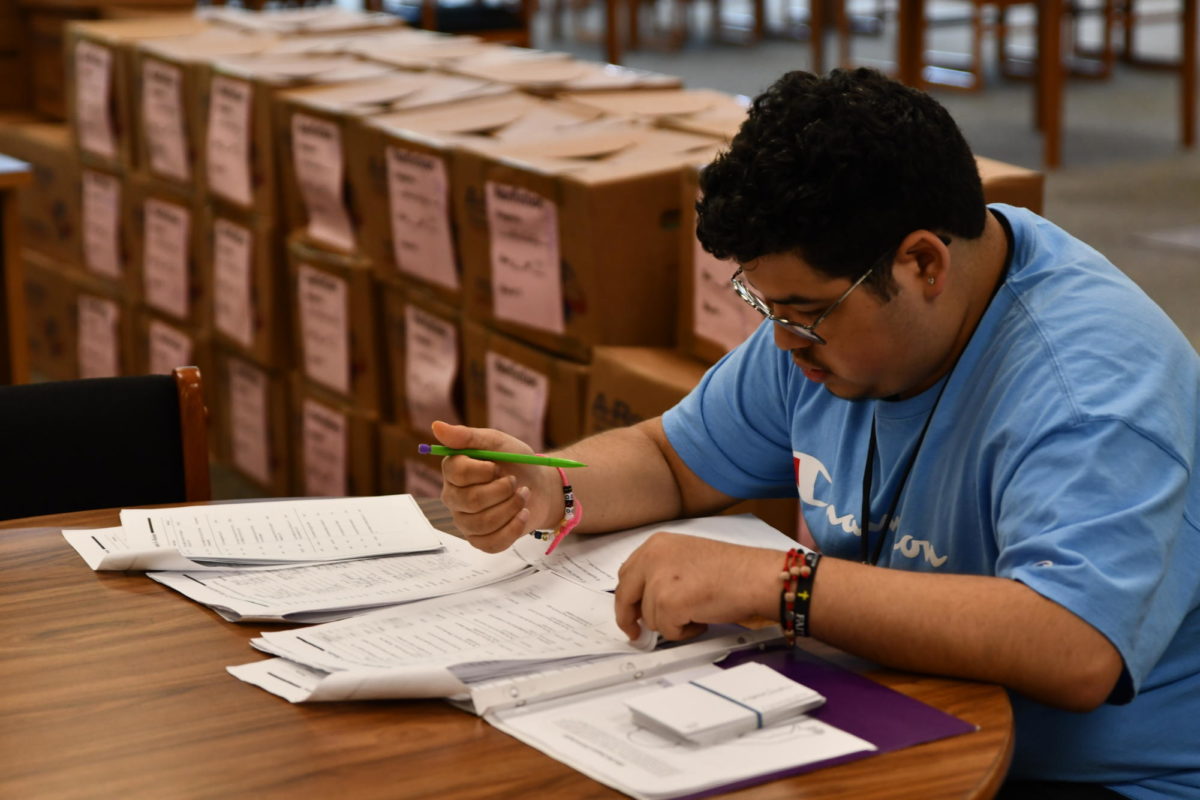 Senior Oscar Nuñez works on schoolwork in the library during fifth period in September. Behind him sat boxes of books that had yet to be unpacked since school-wide construction impacted the library and the number of bookshelves available. 