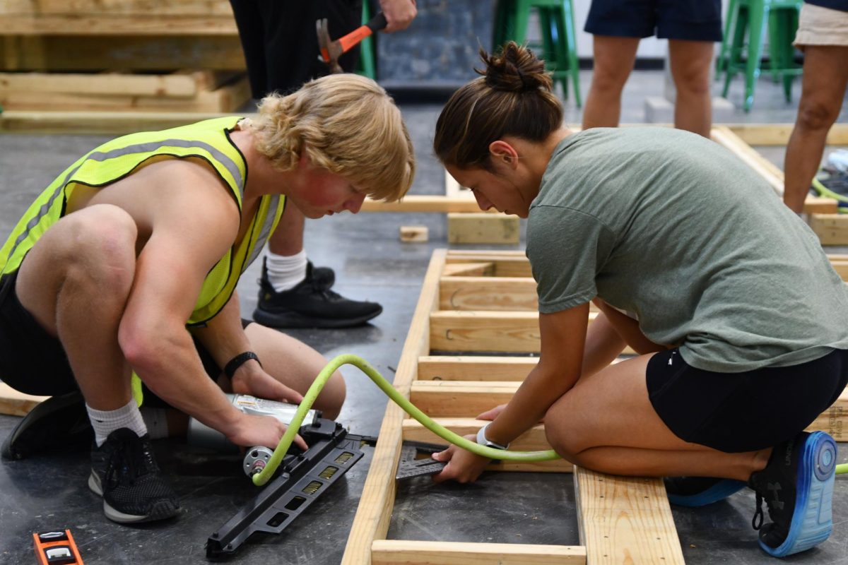Junior Peyton Seay and senior Carmen Ramirez work together to create one of the outside walls of the newest tiny home.