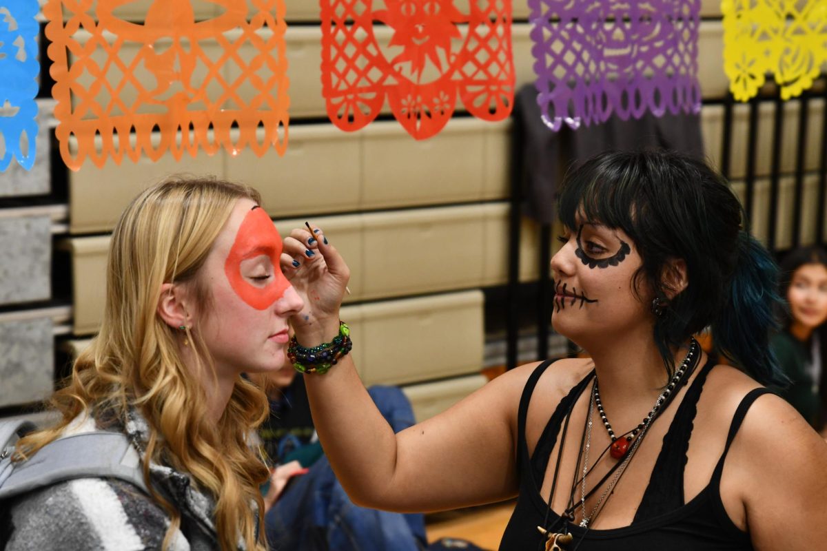 Senior Cas Magee runs a face painting station during last years Spanish Honor Society party. This year, the Art Honor Society will be offering face painting again. Attendees will also get a meal, learn about Latin American countries and celebrate with music.