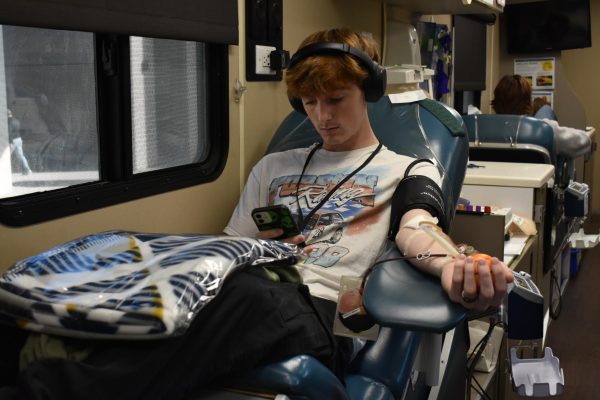 Senior Donovan McClure scrolls on his phone as he has his blood drawn on Nov. 15. The HOSA students hold four blood drives a year on campus. 