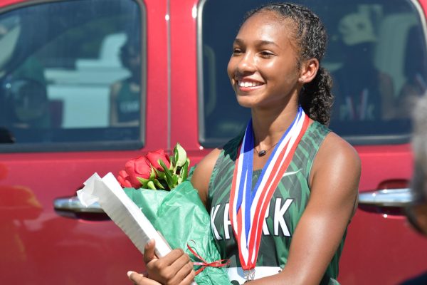 Senior Elina Bailey holds flowers after she collects her first place medal at the District Cross Country Meet at Atascocita High School.