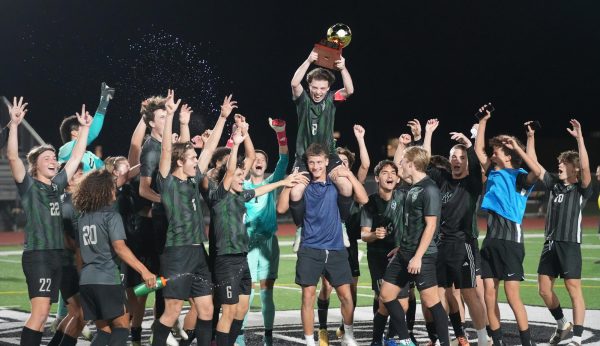 Senior Craig Potter sits on junior Alex Hartnett’s shoulders as he holds the district championship trophy while the team celebrates the win over Dayton and clinching the district title.