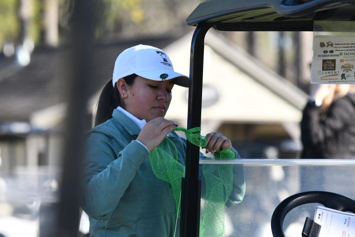 Senior Leah Torres ties a ribbon to her golf cart before the tournament starts. The Humble ISD Classic was held on Feb. 19.