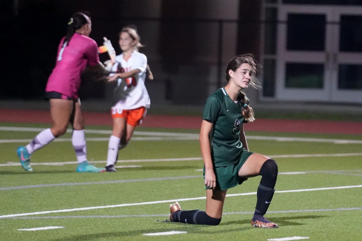 As McKinney North players celebrate in the background, junior forward Flavia Salima Marcano falls to her knee as the final buzzer sounds in the Area playoffs. Kingwood Park lost 2-1, ending the season. 