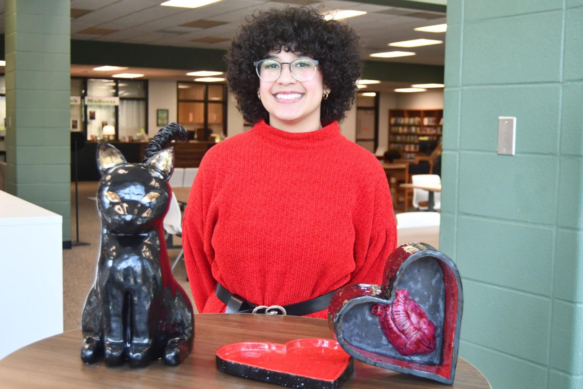 Ana La Rosa Grillo stands with two of the sculptures she has made in art class.