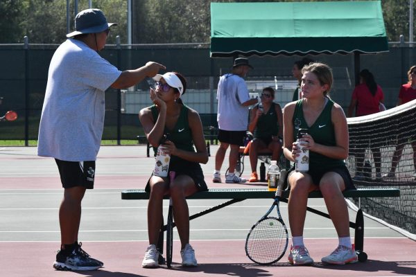 Tennis coach John Macapaz talks to seniors Luvenia Wallace and Brooke OBrien during a match against Porter in the fall. The two won the District doubles title in the spring and advanced to Region.