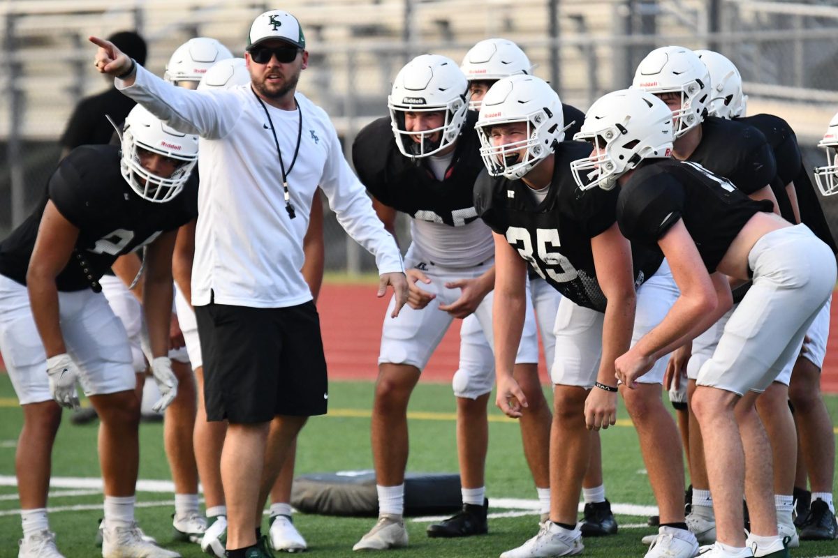 Coach Eric Coovert huddles with Zach Ford, 12, and Jaime Garza, 11, at the Family Night at the Park on Aug. 9. The team ran football drills while family was able to watch. 