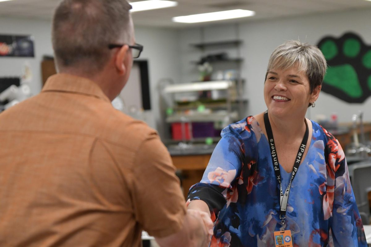 Biology teacher Kristen Lynam shakes a parent’s hand welcoming him into her room during Open House.