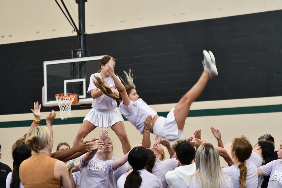 Varsity cheerleaders work on a stunt during class in the third gym. Cheer is one of many organizations who have already utilized the new gym.