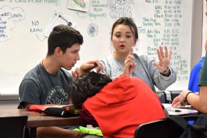 Theater director Brandi Perkins helps students calculate the cost of supplies for a trip to the frozen tundra after watching a video recording of "Frozen the Musical."