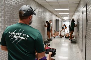 Soccer coach Jess White watches his seventh period soccer class participate in their weight room work out in the athletic building hallway to prepare for the season. The team has been using the hallways to work out while in-sport teams use the gyms. 