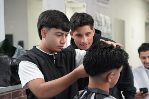 Senior Emmanuel Lopez works on cutting hair as junior Chris Garcia watches closely. The boys spend periods one through three in Barbering class each day. 