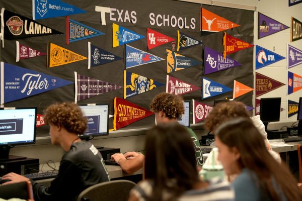 Juniors in AVID class work on projects as a wall displays pendants from colleges and universities across the state. AVID students work on college preparedness with Texas college visits a regular occurrence each year.