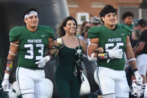 Senior Ivan Reyes and his brother Eduardo are escorted on the field by their mom before their final senior football game at Turner Stadium.