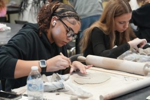 Sophomores Laila Phillips and Katie McCoy sculpt their design for their bowl project.