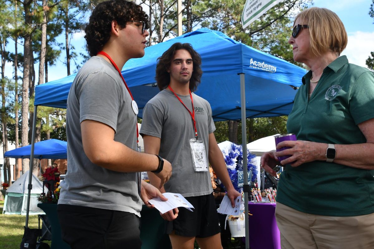 Senior David Gonzalez speaks to a community member at the Kingwood Farmer's Market in Town Center about donating bone marrow.