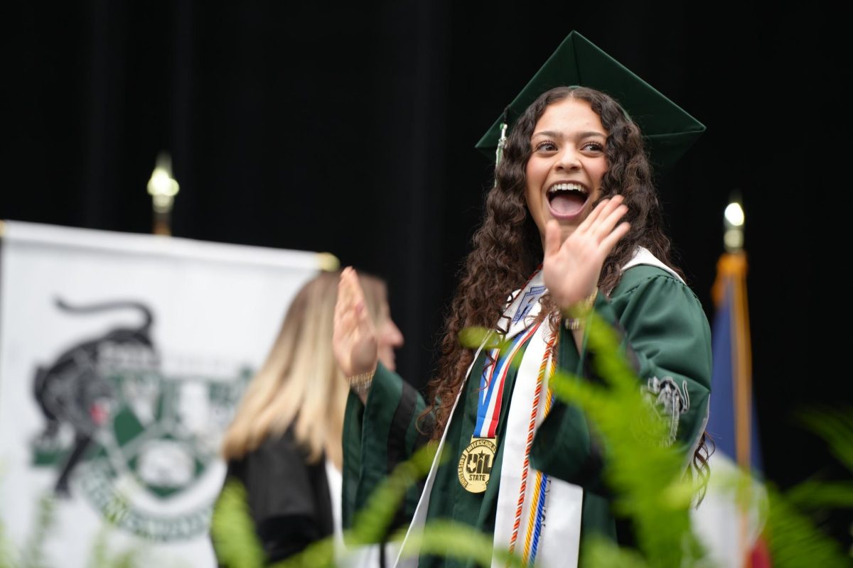 Senior Maddy Miranda celebrates as she walks across the stage to get her diploma on May 24. On graduation day, Miranda wore her state title cheer medal. She will cheer at TCU next year.