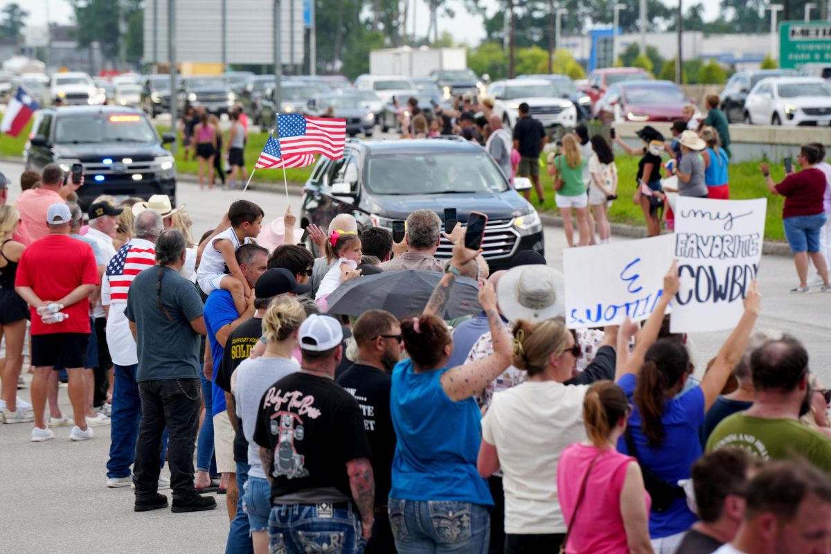 Community members hold up American flags while the procession for Shiloh Wilson passes. The procession for Wilson and his family took place on July 12. The Wilson family died in the Central Texas floods while camping in Kerrville.