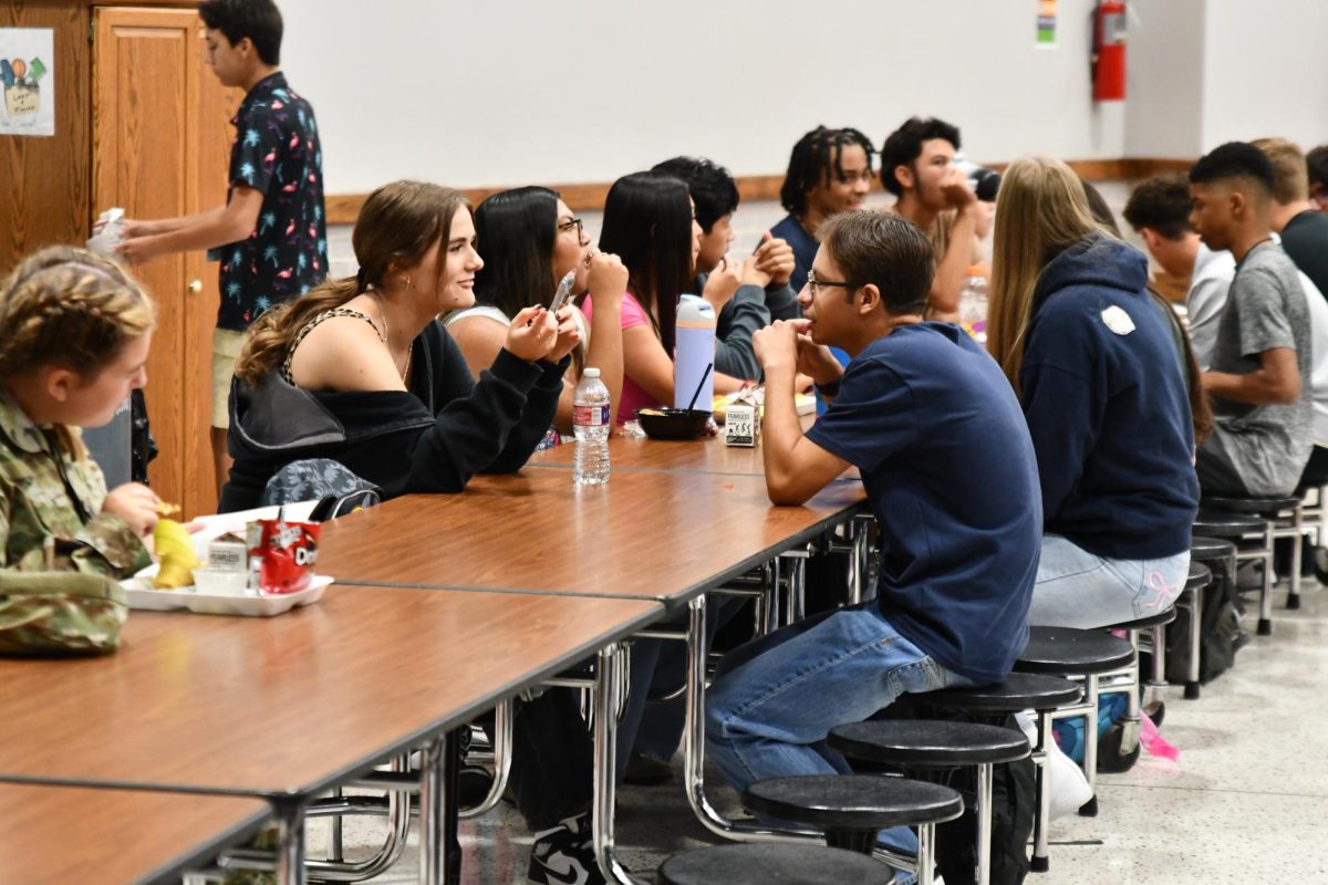 Students talk during lunch, while others read or play cards with friends. The personal communication device ban includes lunch and passing periods. 