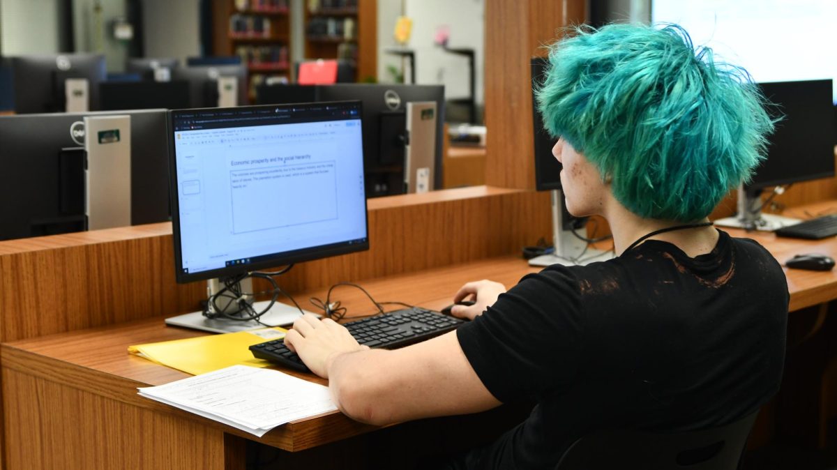 During fifth period, junior Zeke Caldwell works on one of the desktops in the library on Aug. 29. The library has seen an increase in students using computers since the school year started because of the PCD ban. "It's much faster than Chromebooks, and it just makes things so much easier. They're so much help."