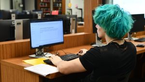 During fifth period, junior Zeke Caldwell works on one of the desktops in the library on Aug. 29. The library has seen an increase in students using computers since the school year started because of the PCD ban. "It's much faster than Chromebooks, and it just makes things so much easier. They're so much help." 